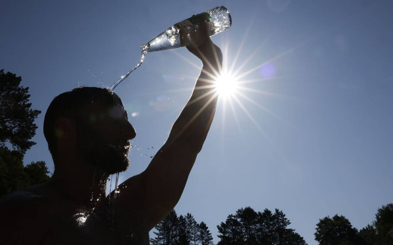 Ein Mann erholt sich von der Hitze, in dem er sich Wasser ins Gesicht spült.