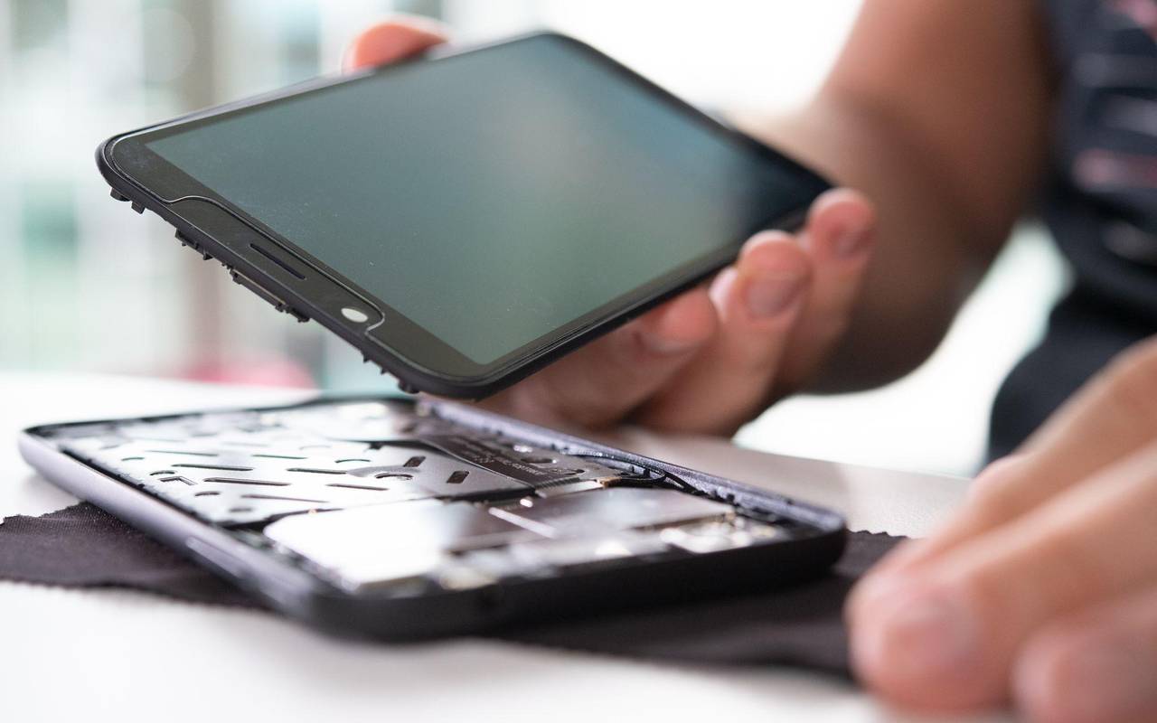 Mann baut ein Smartphone auseinander