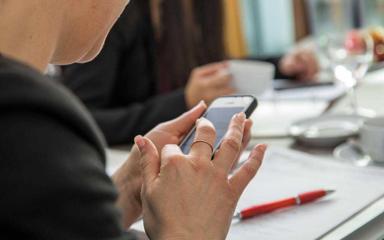 Eine Frau mit Smartphone am Arbeitsplatz