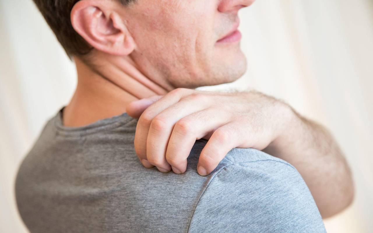 Mann kratzt sich an der Schulter