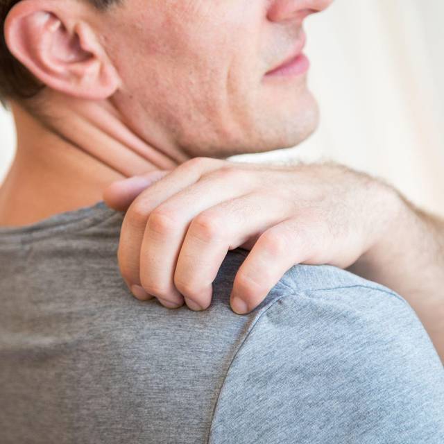 Mann kratzt sich an der Schulter