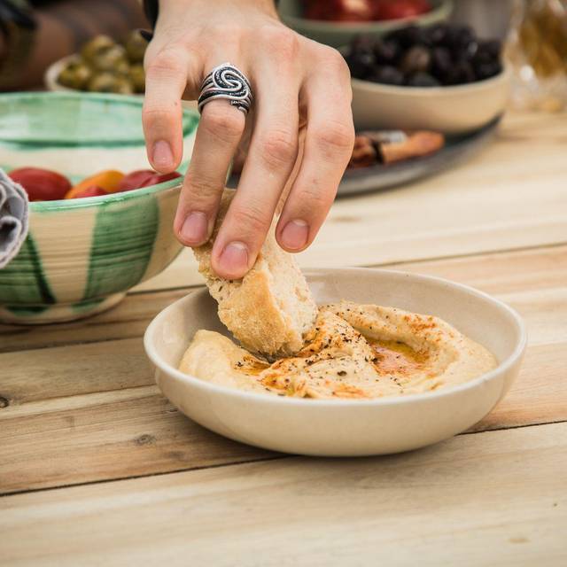 Ein Mann dippt ein Stück Brot in Hummus