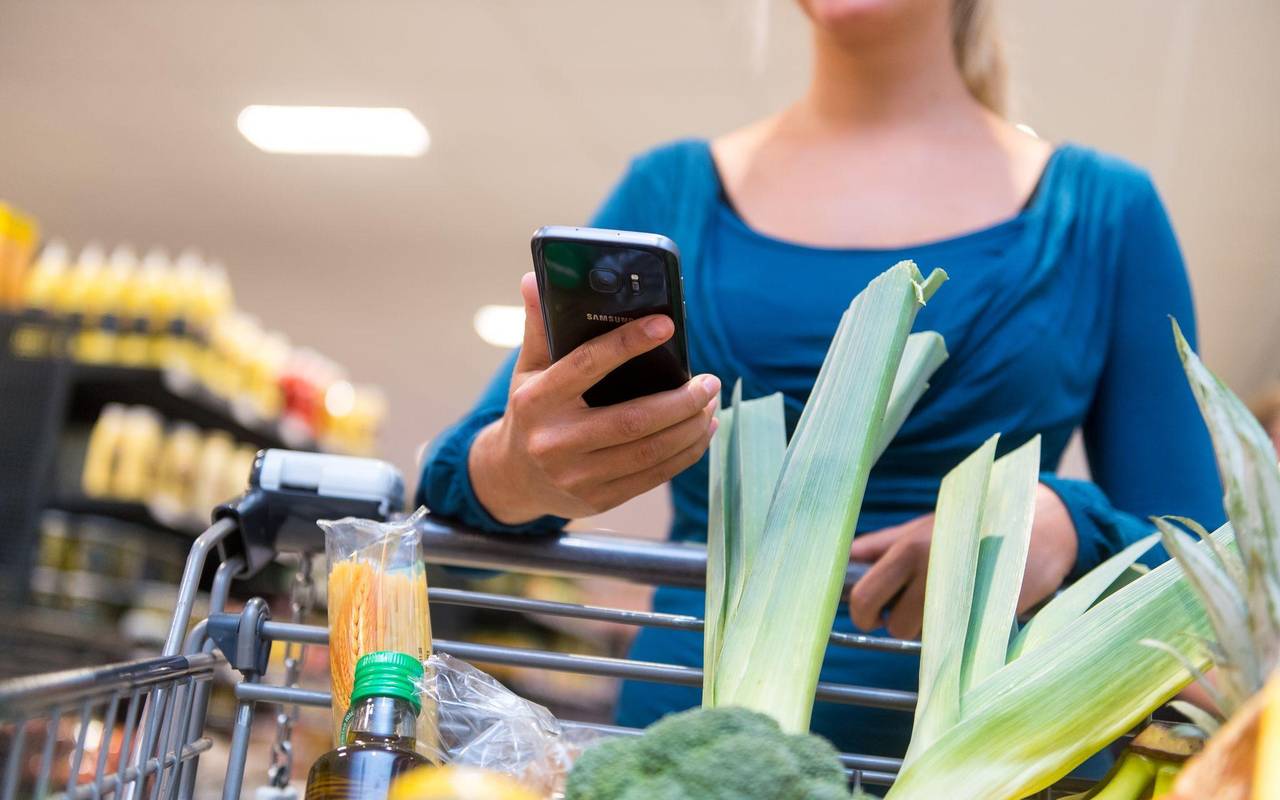 Eine Frau mit Smartphone im Supermarkt