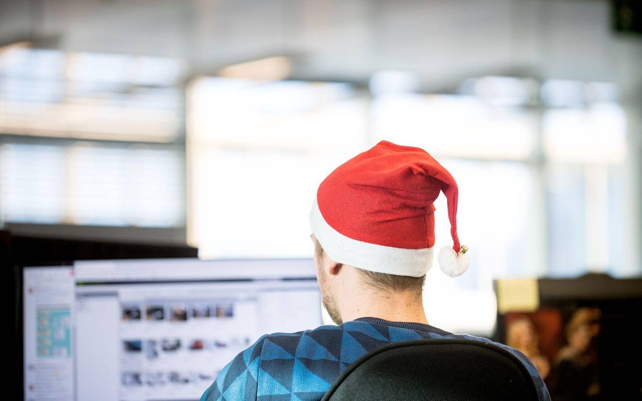 Ein Mann sitzt mit einer Weihnachtsmütze in Büro
