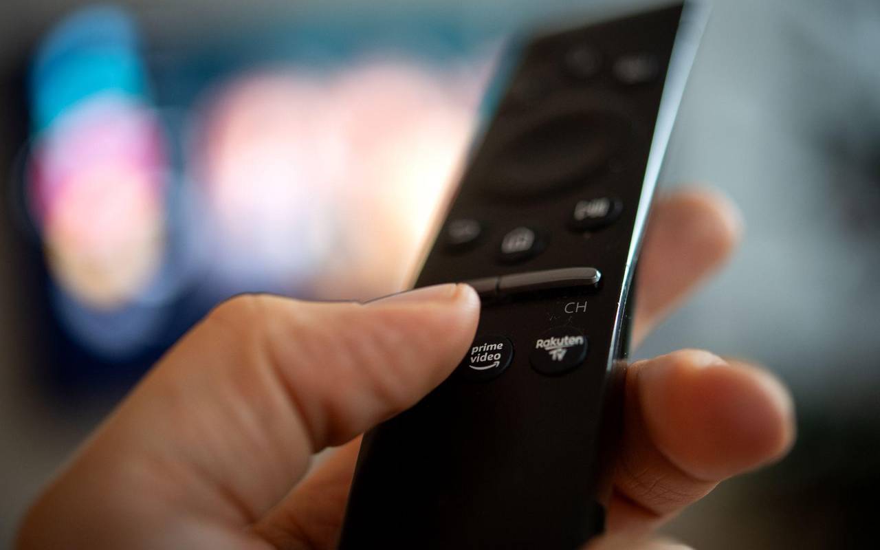 Ein Mann hält eine Fernbedienung mit der Aufschrift Amazon Prime