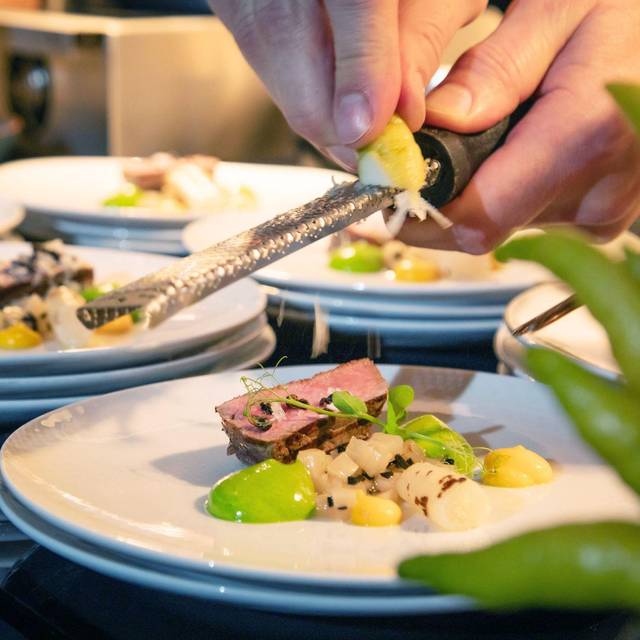 Koch reibt Zesten der Zitrusfrucht Buddhas Hand über ein Menü