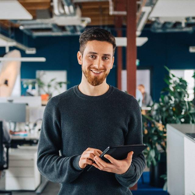 Ein Mann mit Tablet in einem Großraumbüro