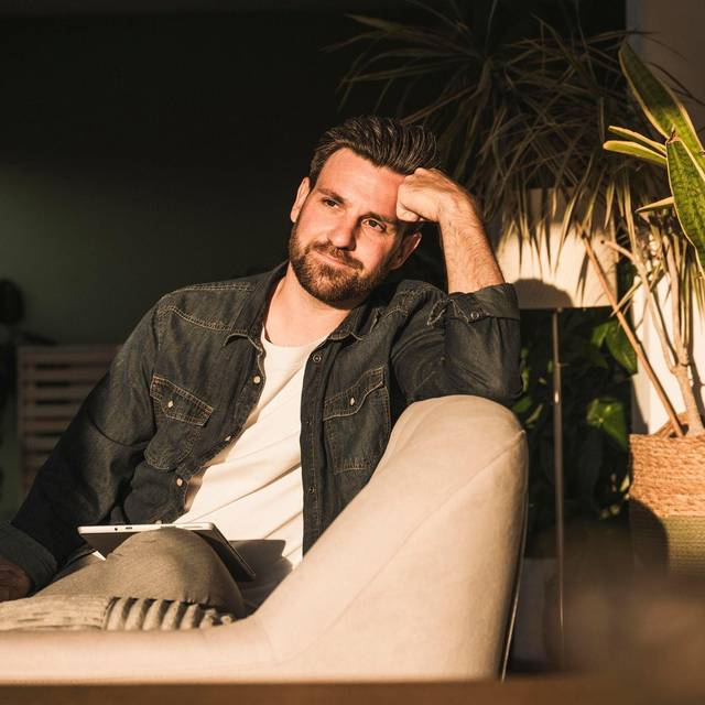 Mann sitzt gedankenvoll auf einer Couch