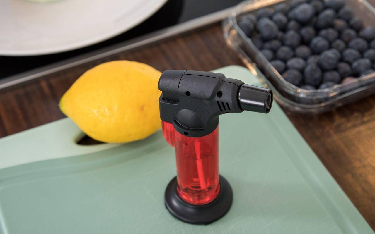 Ein Bunsenbrenner steht neben einer Zitrone und Blaubeeren