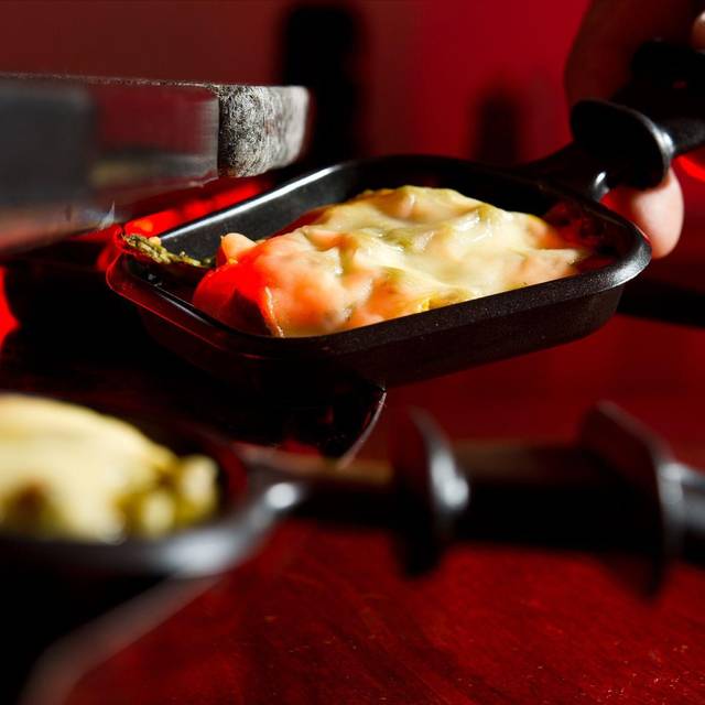 Mann hält ein Raclette-Pfännchen in der Hand