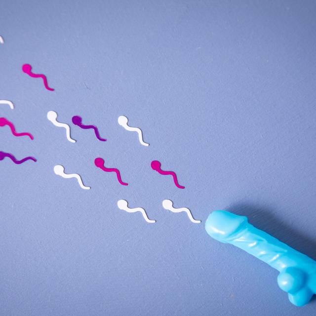 Konfetti in Sperma-Form liegt neben einem Penis-Strohhalm