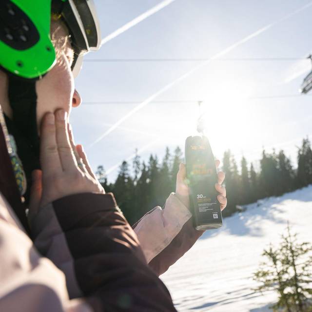 Eine Skifahrerin trägt Sonnencreme auf
