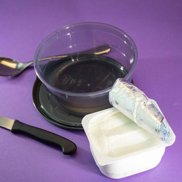 Ein Becher Quark steht neben einer Schüssel