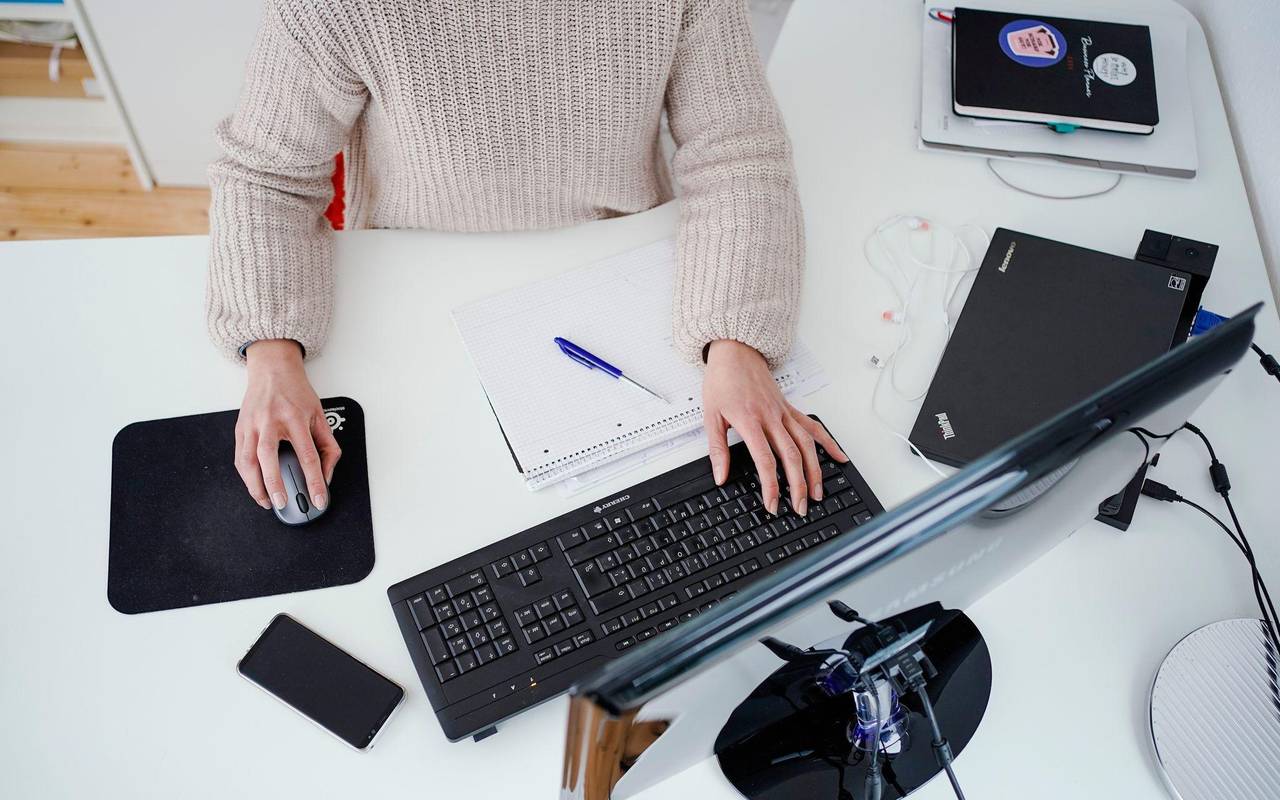 Eine Person arbeitet im Homeoffice an einem Schreibtisch