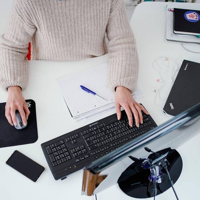 Eine Person arbeitet im Homeoffice an einem Schreibtisch