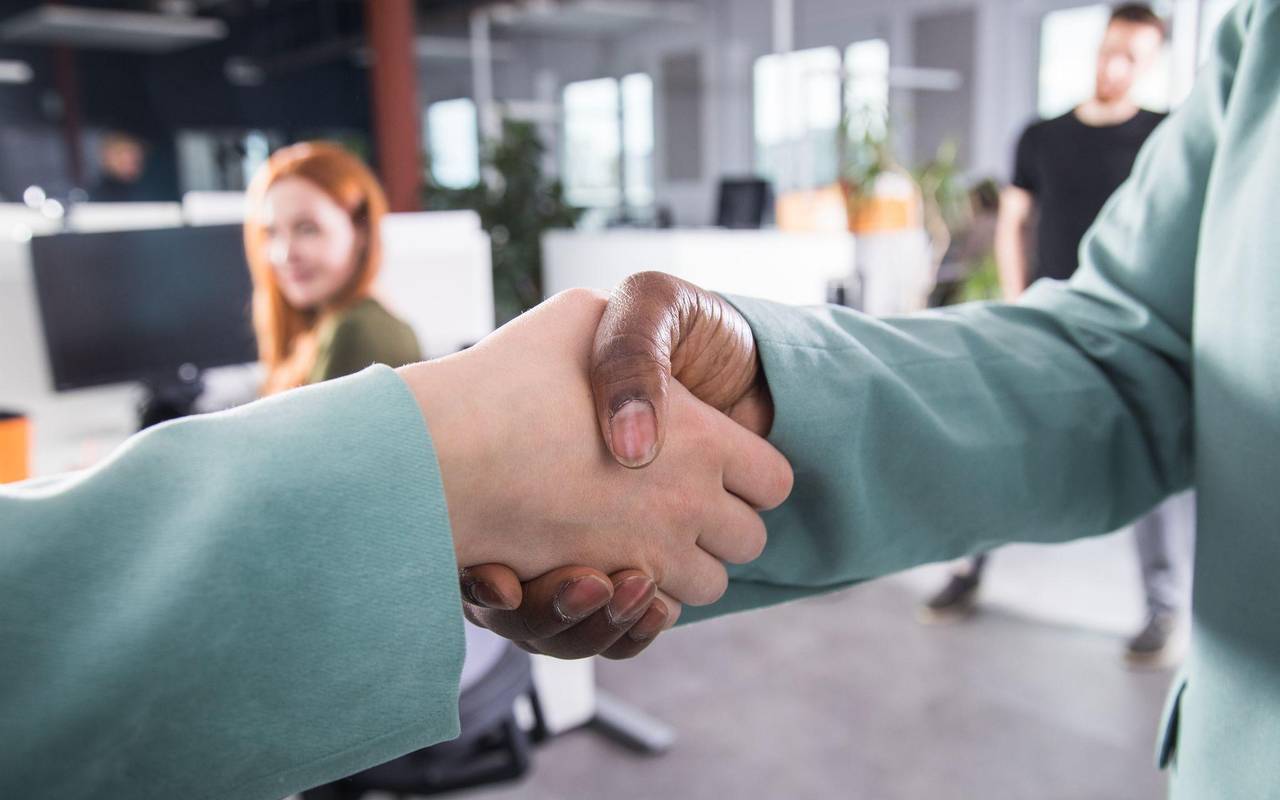 Zwei Frauen reichen sich im Büro die Hände