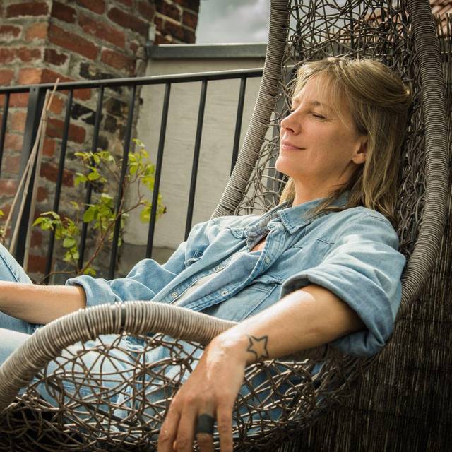 Frau sitzt entspannt im Hängesessel auf einer Terrasse