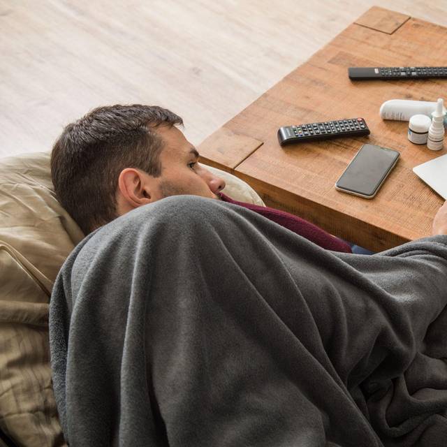 Ein Mann mit Erkältung bedient ein Laptop