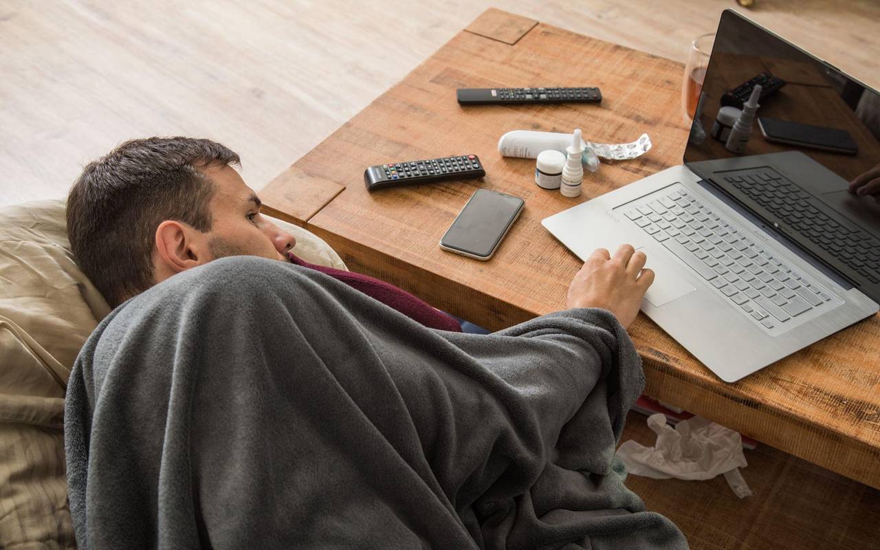 Ein Mann mit Erkältung bedient ein Laptop