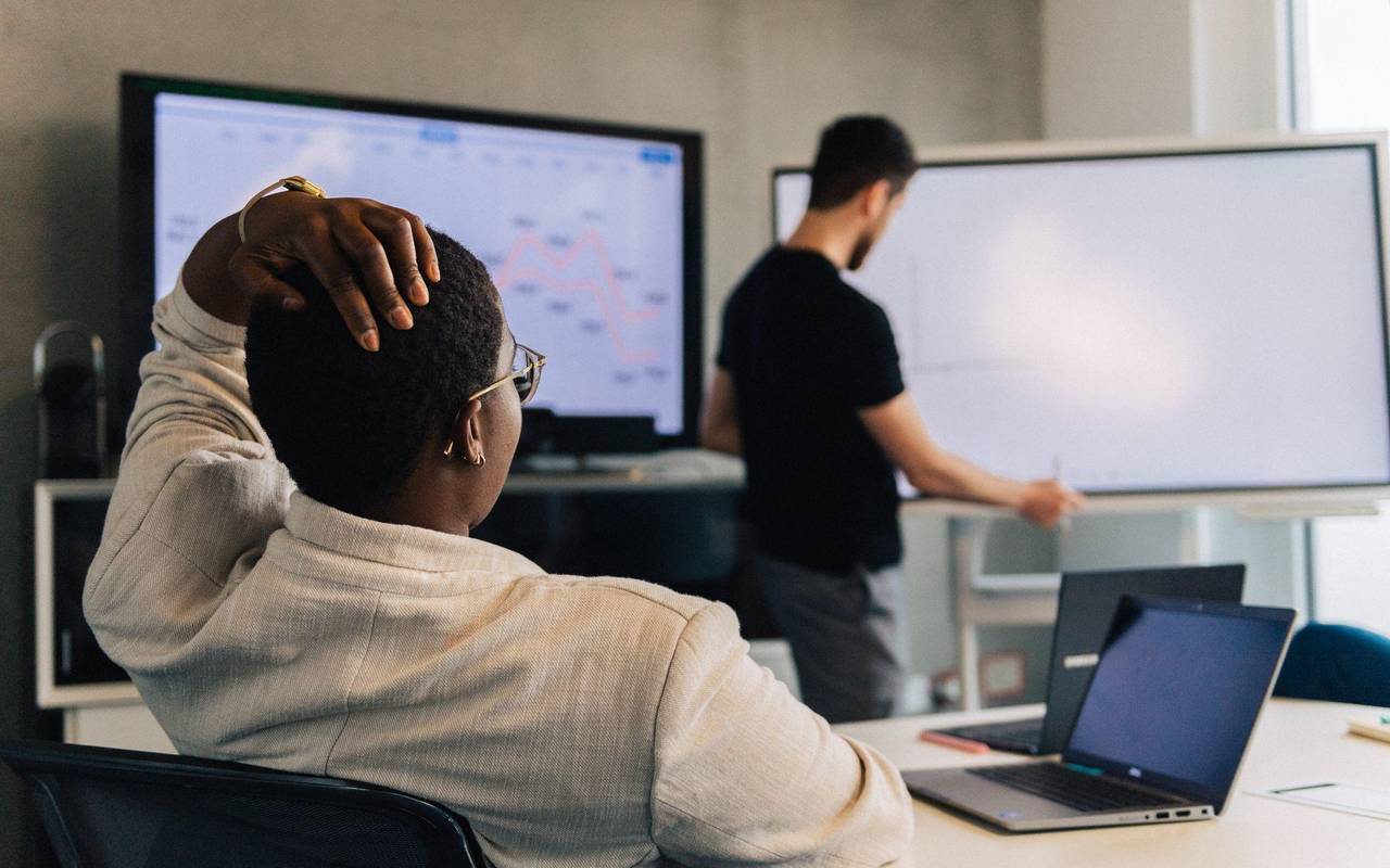 Eine Frau fasst sich an den Kopf in einem Meetingraum