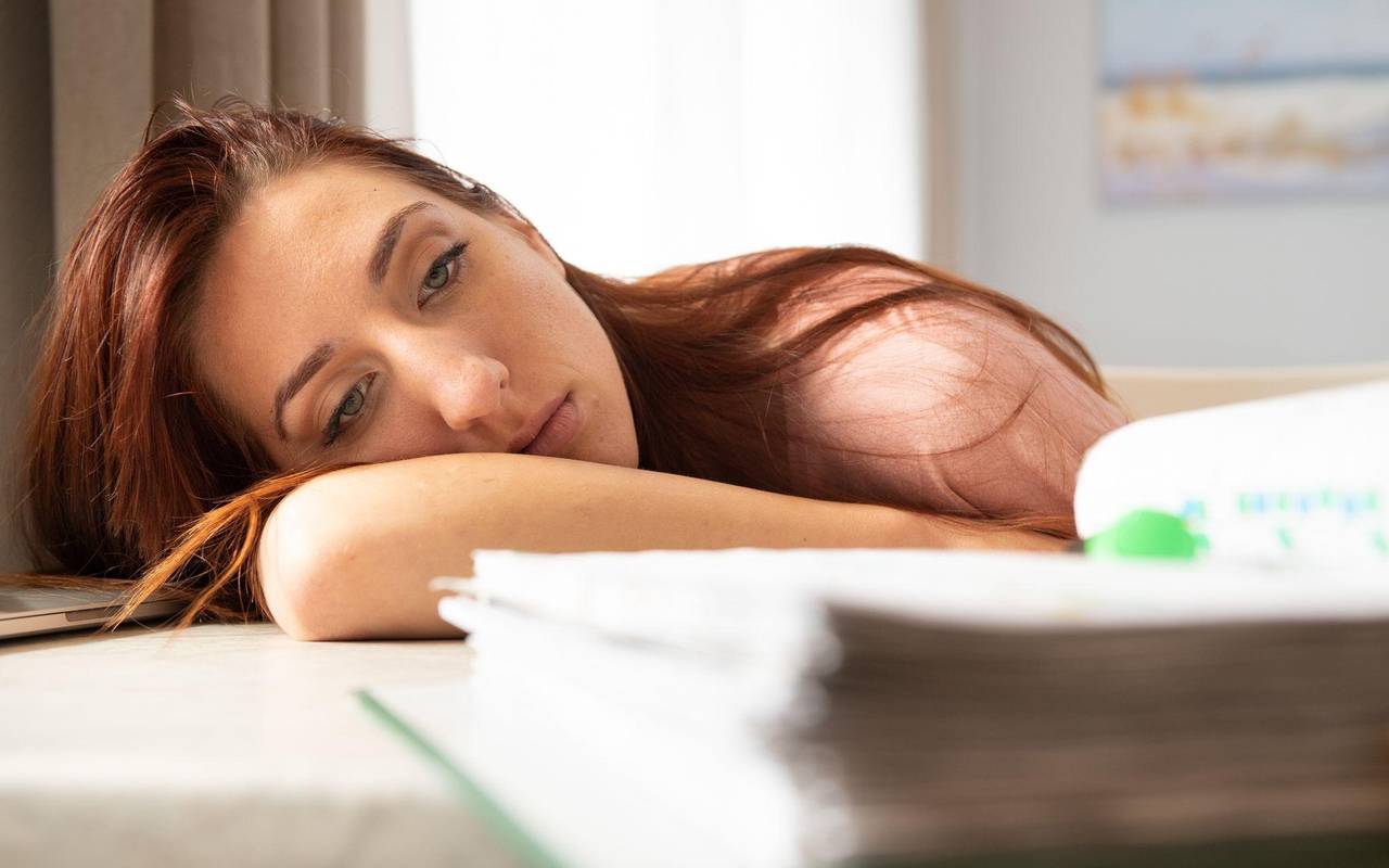 Eine junge Frau schaut unmotiviert auf Aktenordner