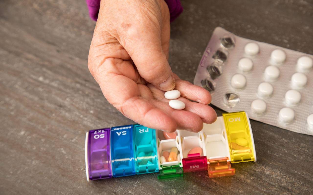 Seniorin nimmt Tabletten aus einer Pillendose