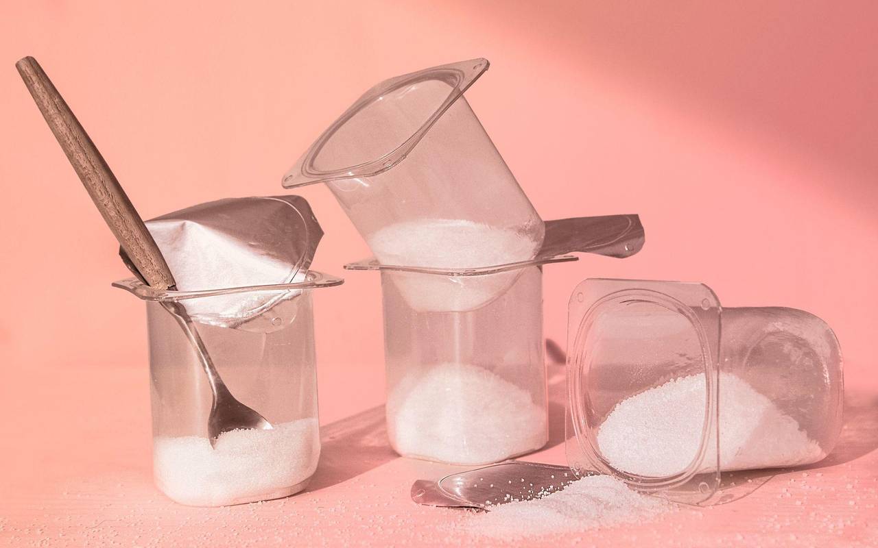 Mit Zucker gefüllte Joghurtbecher stehen auf einem Tisch