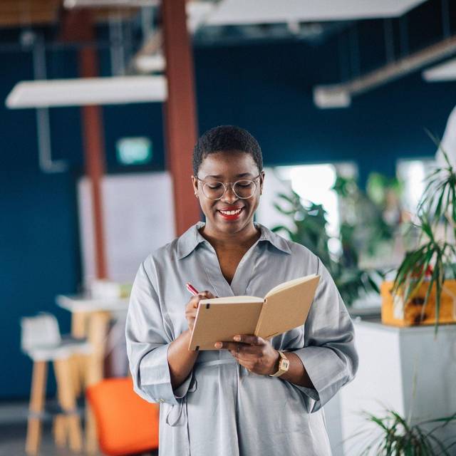 Eine junge Frau schreibt in ein Notizheft