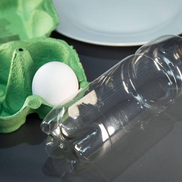 Ein Ei liegt neben einer Plastikflasche