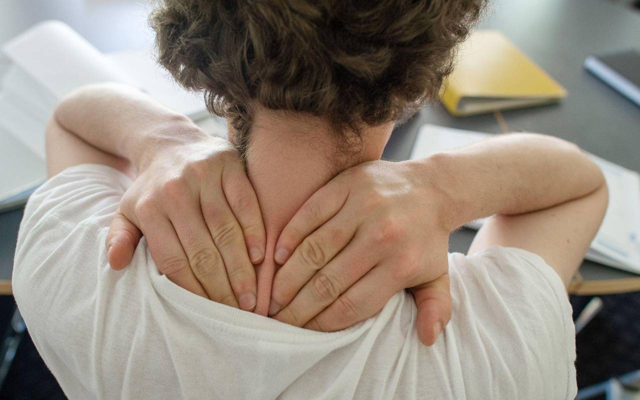 Ein Mann greif tmi beiden Händen seinen Nacken