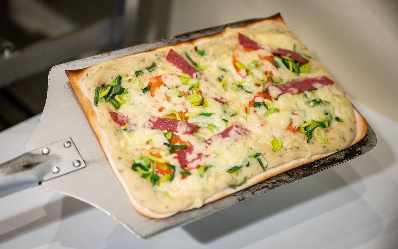 Ein Flammkuchen mit Tomaten und Salami