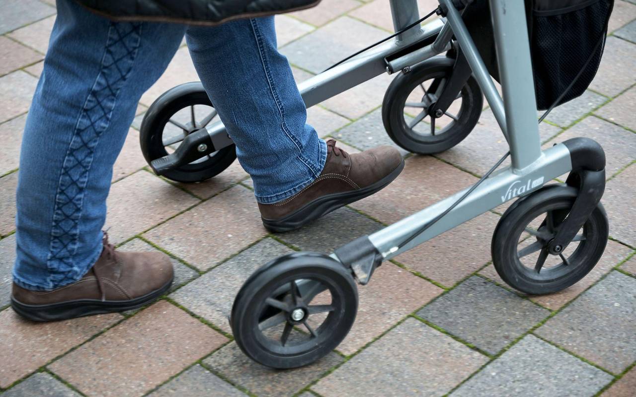 Seniorin fährt mit ihrem Rollator auf einem gepflasterten Weg