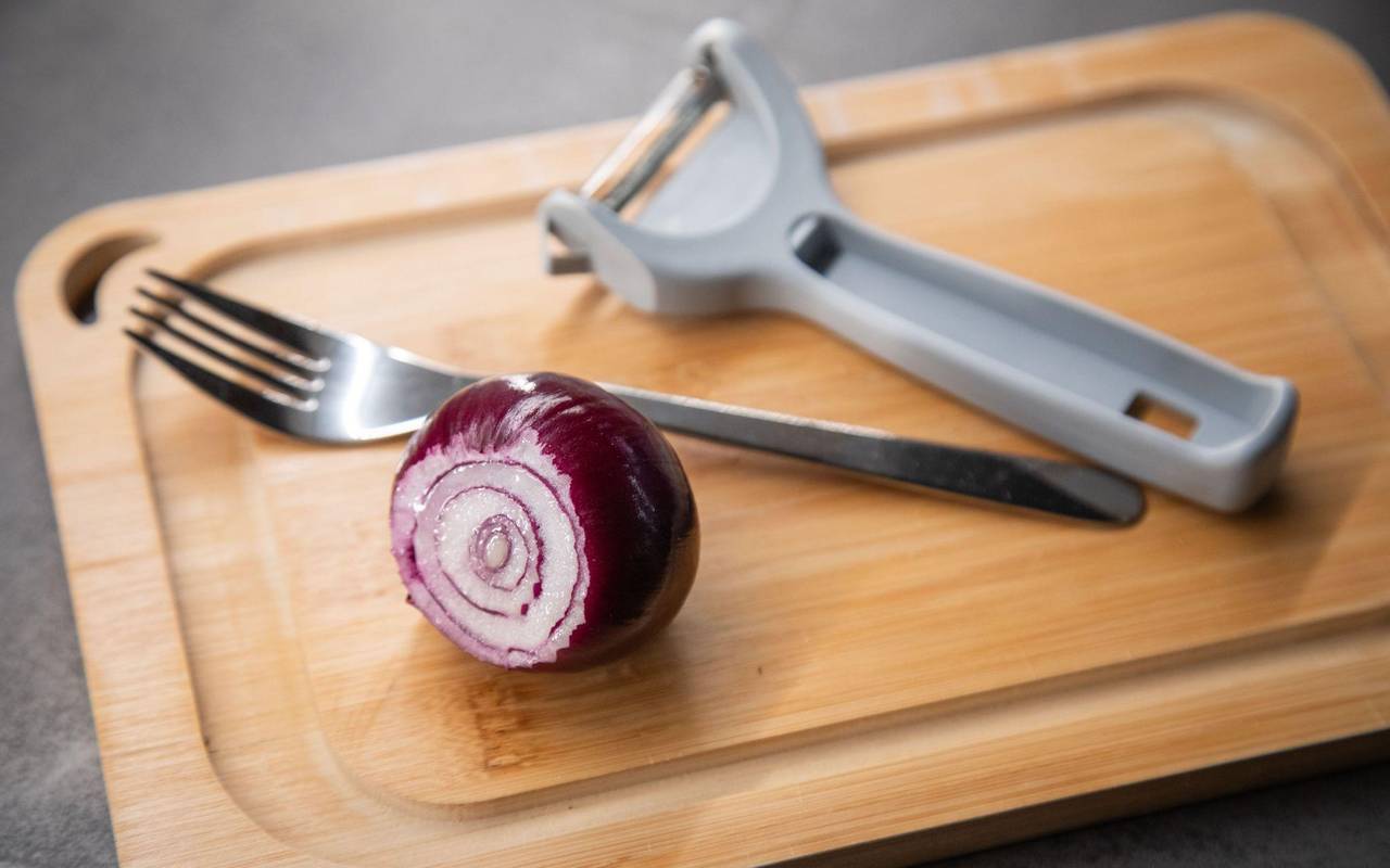 Zwiebel und ein Sparschäler liegen auf einem Tisch
