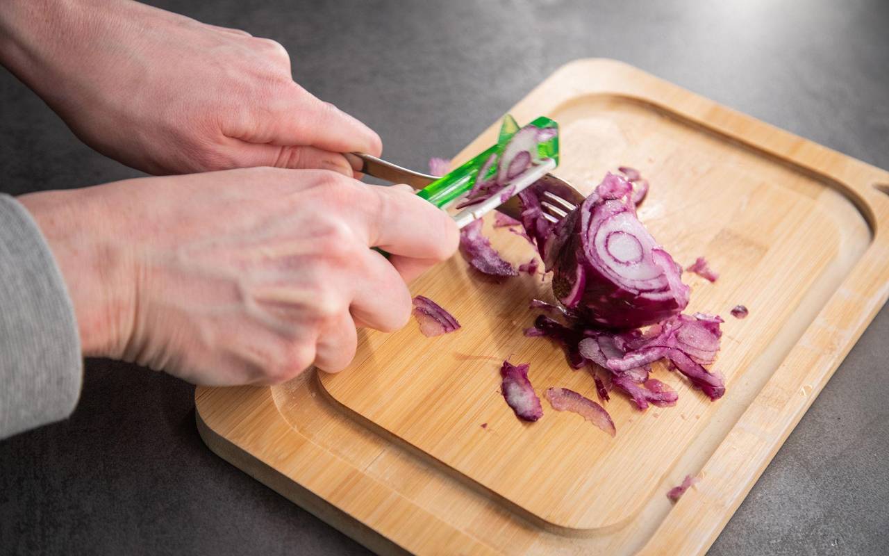 Ein Sparschäler wird über eine Zwiebel gezogen
