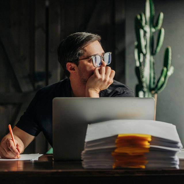 Ein Mann arbeitet am Laptop und sieht aus dem Fenster