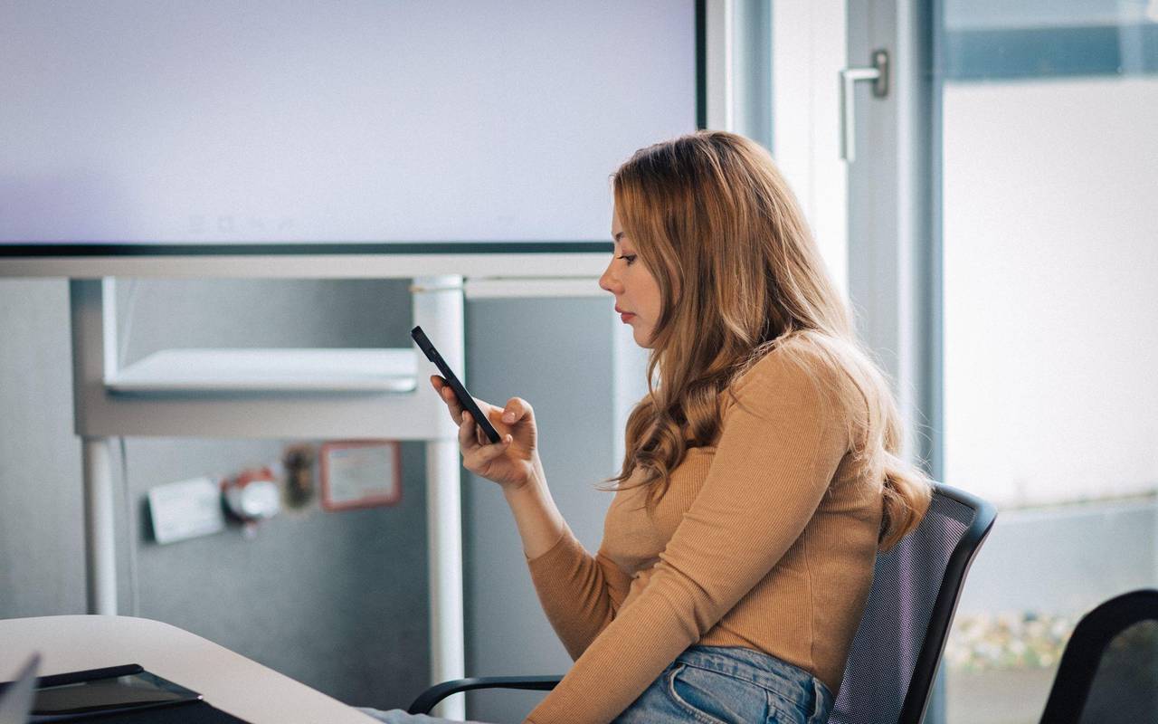 Junge Frau mit Smartphone im Büro