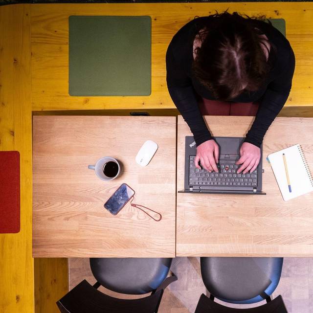 Frau sitzt im Homeoffice am Küchentisch und arbeitet am Laptop