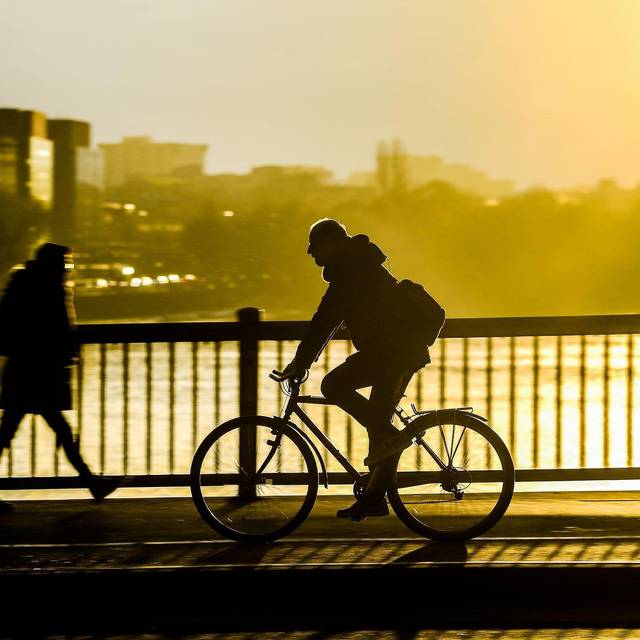 Fahrradfahrer fährt im Sonnenuntergang über eine Brücke