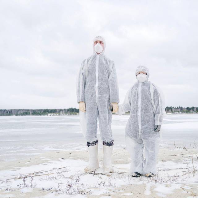 Ein Mann und ein Kind in Schutzanzügen halten Händchen