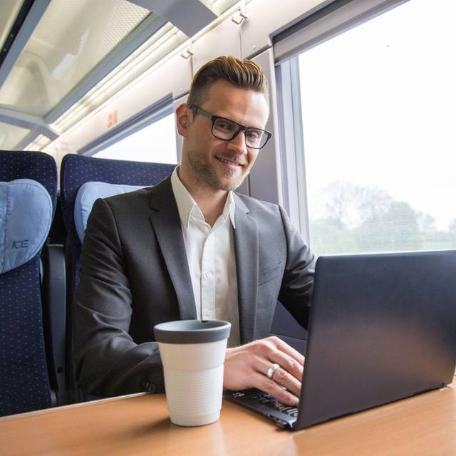 Ein mann arbeitet in einem Zug an einem Laptop