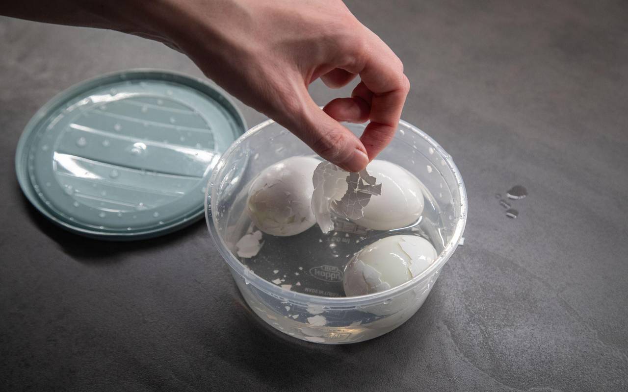 Frau pellt Eier in einer Schale Wasser