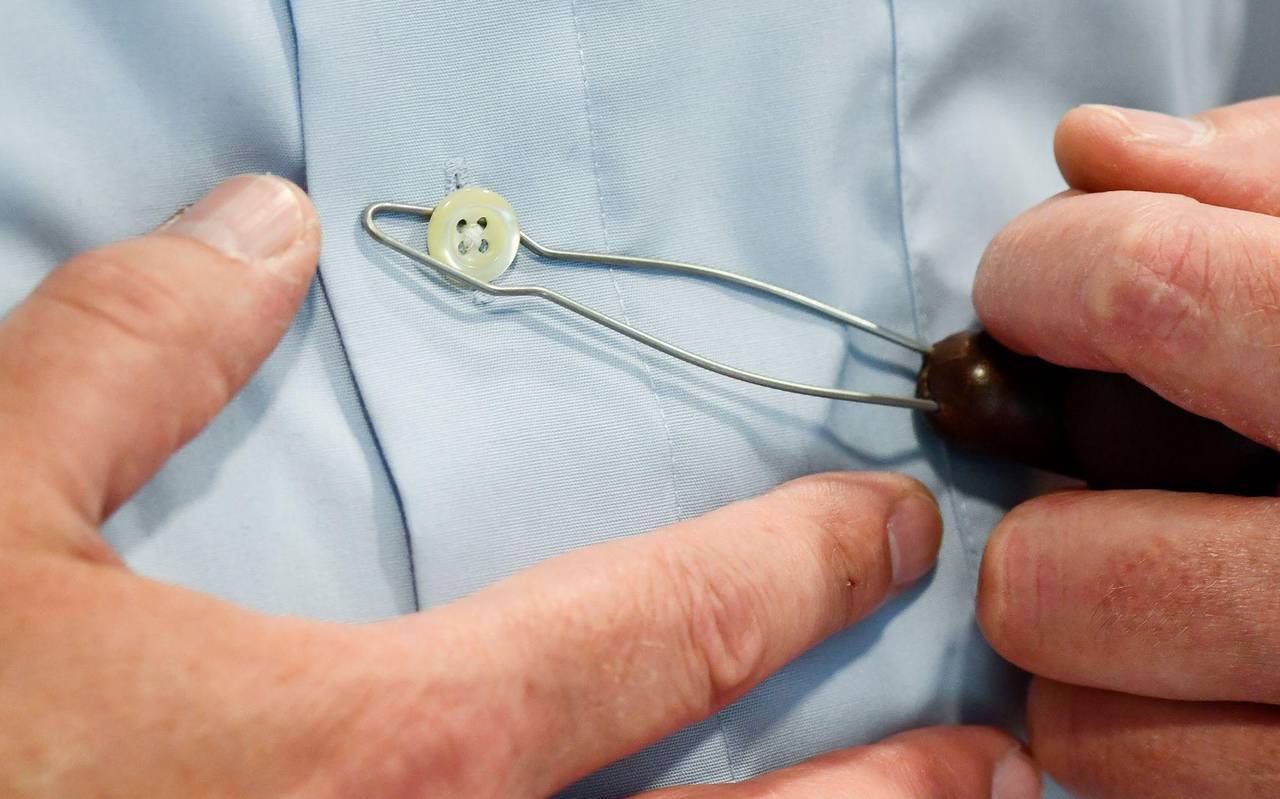 Mann nutzt eine Anziehhilfe, um den Knopf an einem Hemd zu öffnen