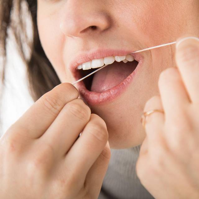 Eine Frau benutzt Zahnseide