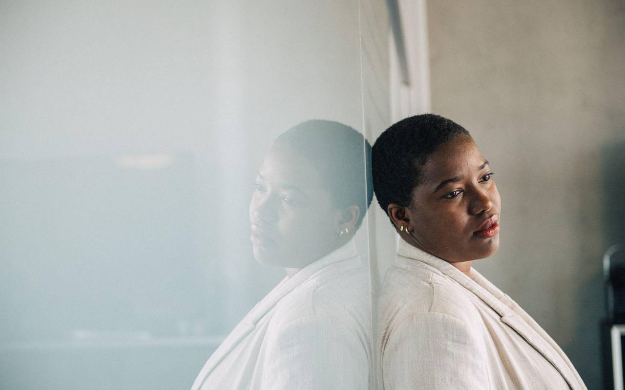 Eine junge Frau lehnt nachdenklich an einer Glaswand