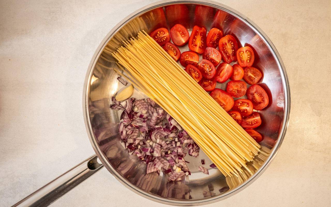 Spaghetti, Tomaten und Zwiebeln in einer Pfanne
