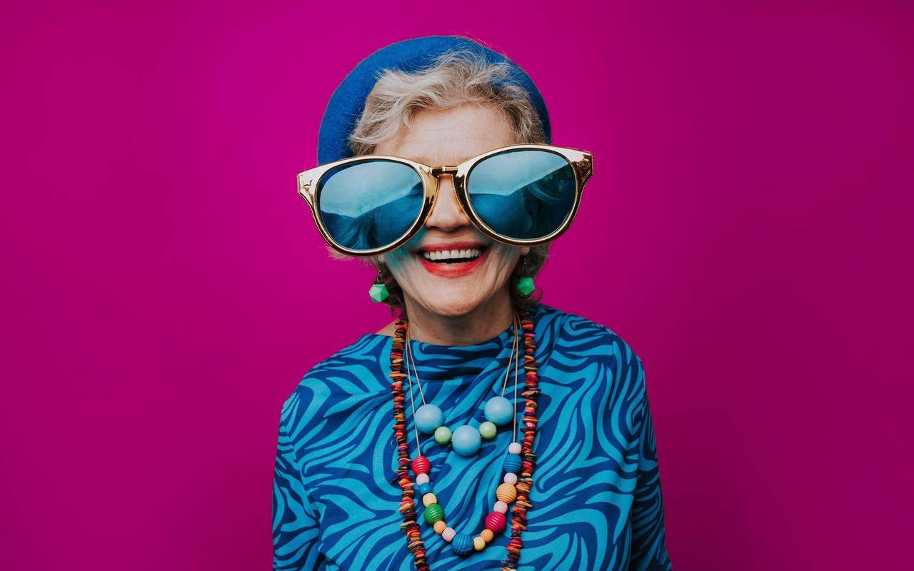 Eine glückliche Seniorin mit übergroßer Sonnenbrille