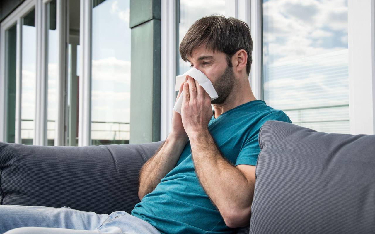 Ein Mann putzt sich die Nase