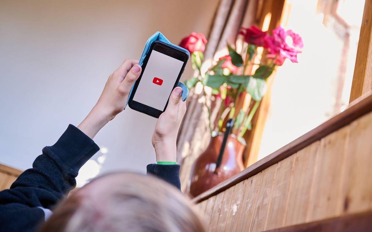 Junge öffnet auf seinem Smartphone die App von YouTube