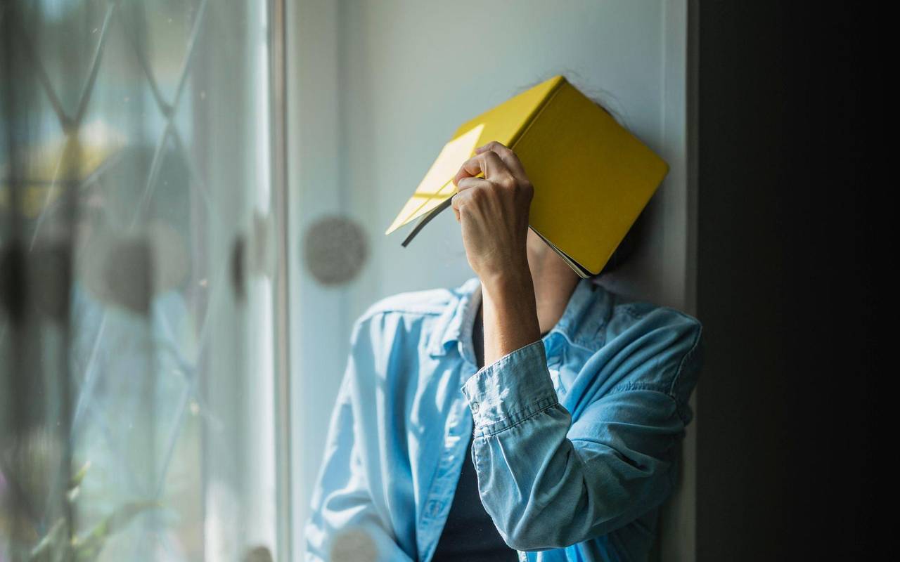 Eine Frau verbirgt ihr Gesicht hinter einem Notizheft