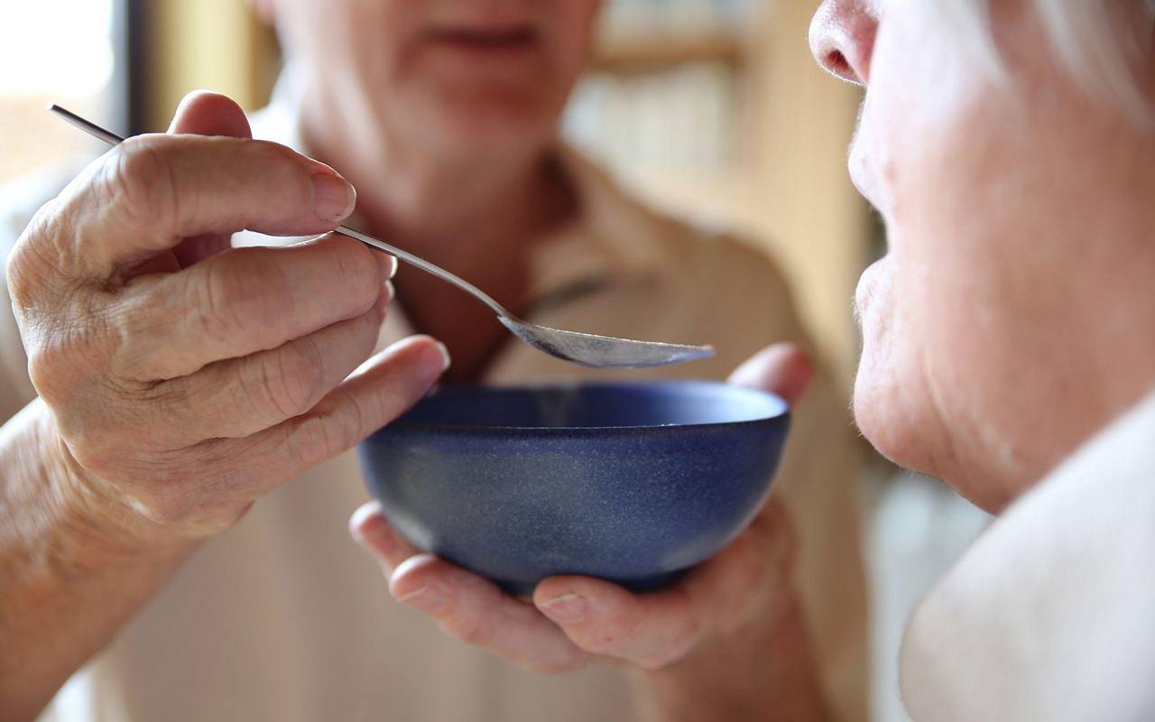 Ein Mann gibt einer zu pflegenden Person etwas zu essen